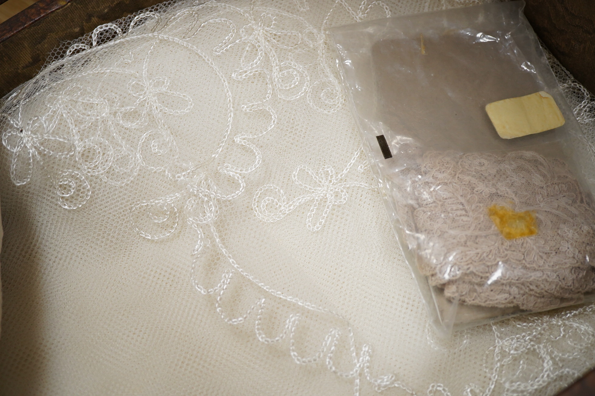A small box/trunk containing mixed crochet, embroidered anglaise and drawn thread table linens, christening gown, damask cloths and various pieces of lace etc.Ornate circular cloth 112cm diameter. Condition - most need r